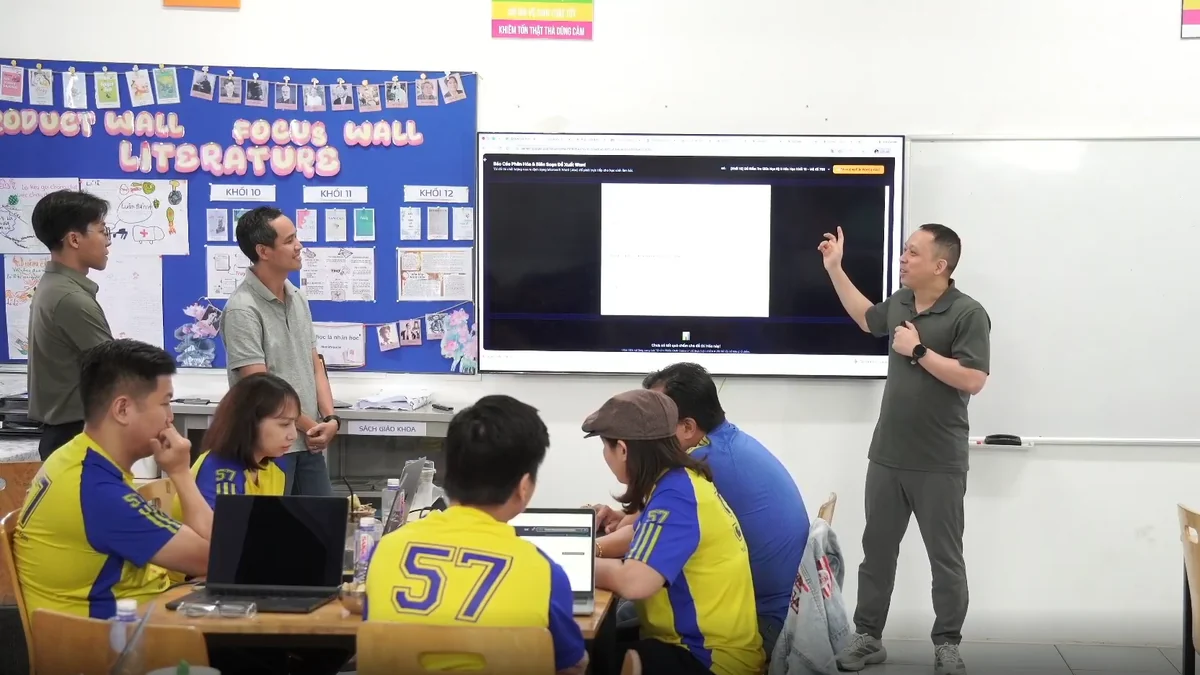 Buổi tập huấn giáo viên Trường Việt Anh — một thầy đứng trình bày trước màn hình lớn đang chiếu công cụ AI phân hóa và biên soạn đề kiểm tra xuất ra file Word, các giáo viên ngồi quanh bàn với máy tính xách tay