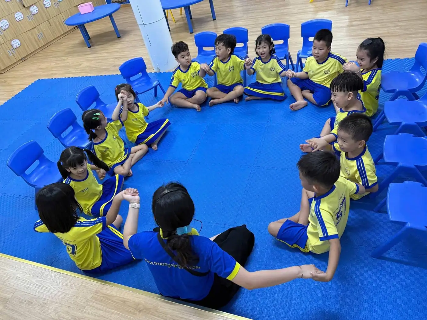 Trẻ lớp Lá nắm tay nhau thành vòng tròn cùng cô giáo trong giờ Morning Meeting